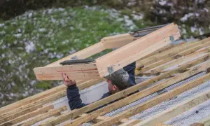 Pracownik montuje drewnianą ramę okna dachowego na konstrukcji dachu. To kluczowy etap, jak zamontować okno dachowe.