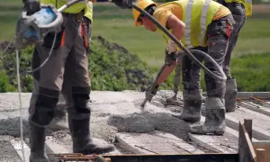 Budowlańcy w kamizelkach i kaskach wylewają beton na strop. Prawidłowe wykonanie to klucz do tego, jak dbać o świeży strop.