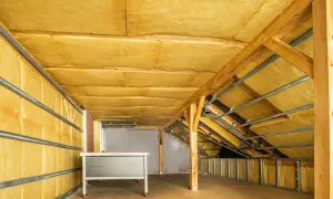 Poddasze ocieplone wełną mineralną od wewnątrz. Widoczne drewniane krokwie i metalowe profile, przygotowanie do dalszych prac wykończeniowych.
