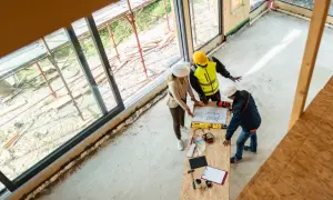 Architekci omawiają projekt, ustalając, ile kosztuje strop drewniany. Na stole plany, narzędzia i próbki materiałów.