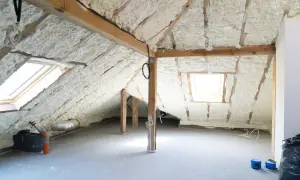 Poddasze z pianką PUR, gotowe do zabudowy skosów. Widać okna dachowe i drewnianą konstrukcję.
