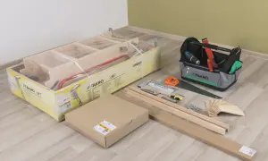 Zestaw do montażu schodów strychowych FAKRO LWT: drabina w opakowaniu, narzędzia, śruby i drewniane elementy.