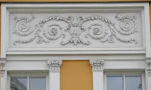 Eleganckie sztukaterie nad oknami to inspiracja, jak ozdobić ścianę zewnętrzną. Wzory liści i winogron dodają klasy.