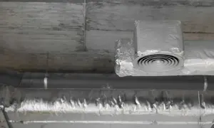 Ocieplanie rur wentylacyjnych na poddaszu folią aluminiową. Widoczny okrągły nawiewnik.