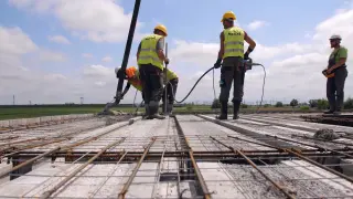 Budowa stropu Teriva: pracownicy wylewają beton. Obraz pokazuje, jak obliczyć beton na strop teriva.