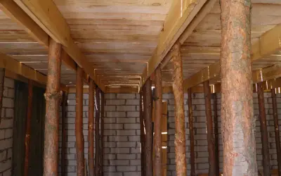 Drewniane stemple pod stropem, tworzące rusztowanie. W tle ściana z pustaków.