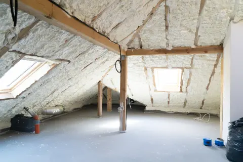 Poddasze z pianką PUR, gotowe do zabudowy skosów. Widać okna dachowe i drewnianą konstrukcję.