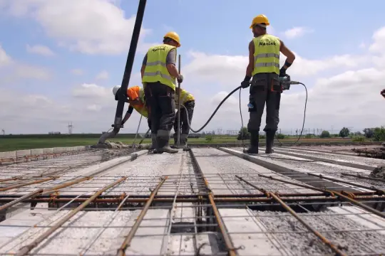 Budowa stropu Teriva: pracownicy wylewają beton. Obraz pokazuje, jak obliczyć beton na strop teriva.