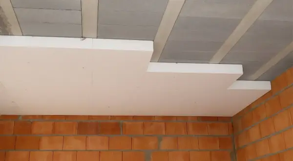 Płyty styropianowe montowane pod betonowym stropem to sposób, jak ocieplić strop. Widoczne ceglane ściany.