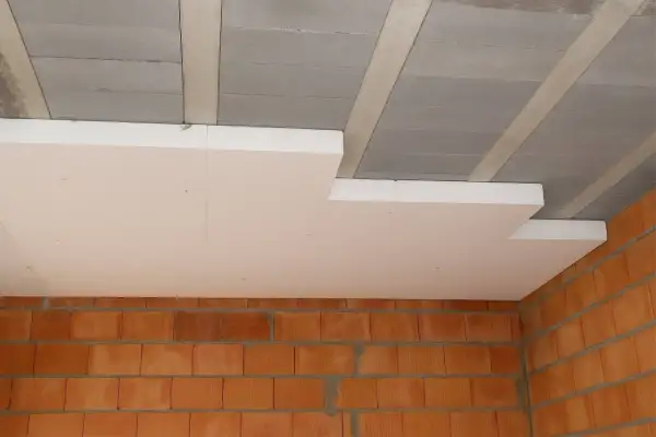 Płyty styropianowe montowane pod betonowym stropem to sposób, jak ocieplić strop. Widoczne ceglane ściany.